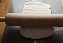 The dough being rolled into a rectangular sheet, working from the middle
